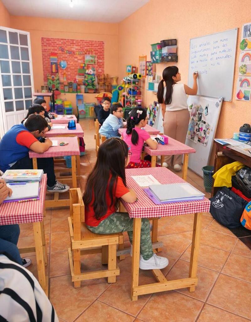 varios niños sentados en un aula de clases viendo hacia el pizarrón