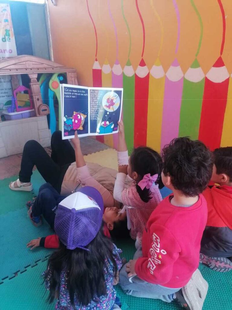 varios niños reunidos acostados leyendo un libro