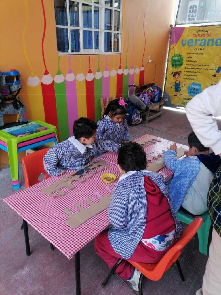 niños con bata armando una corona de cartón