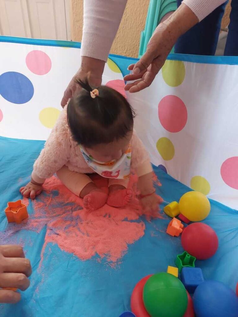 bebe en una tina jugando con arena