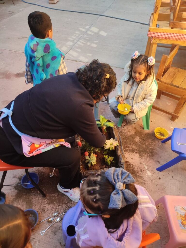maestra con alumnos plantando suculentas