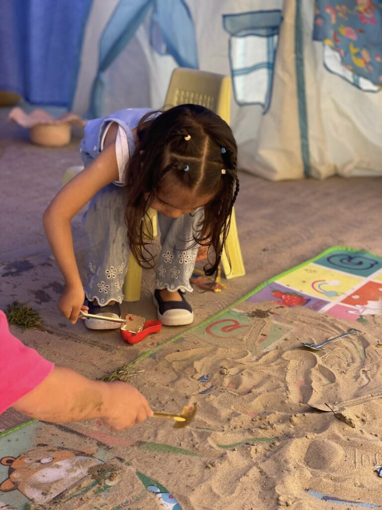niña jugando con arena como parte de proceso de su aprendizaje